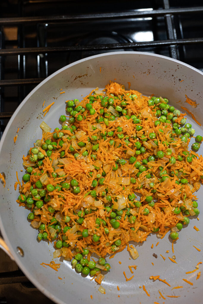 Peas and shredded carrots cooked in a pan