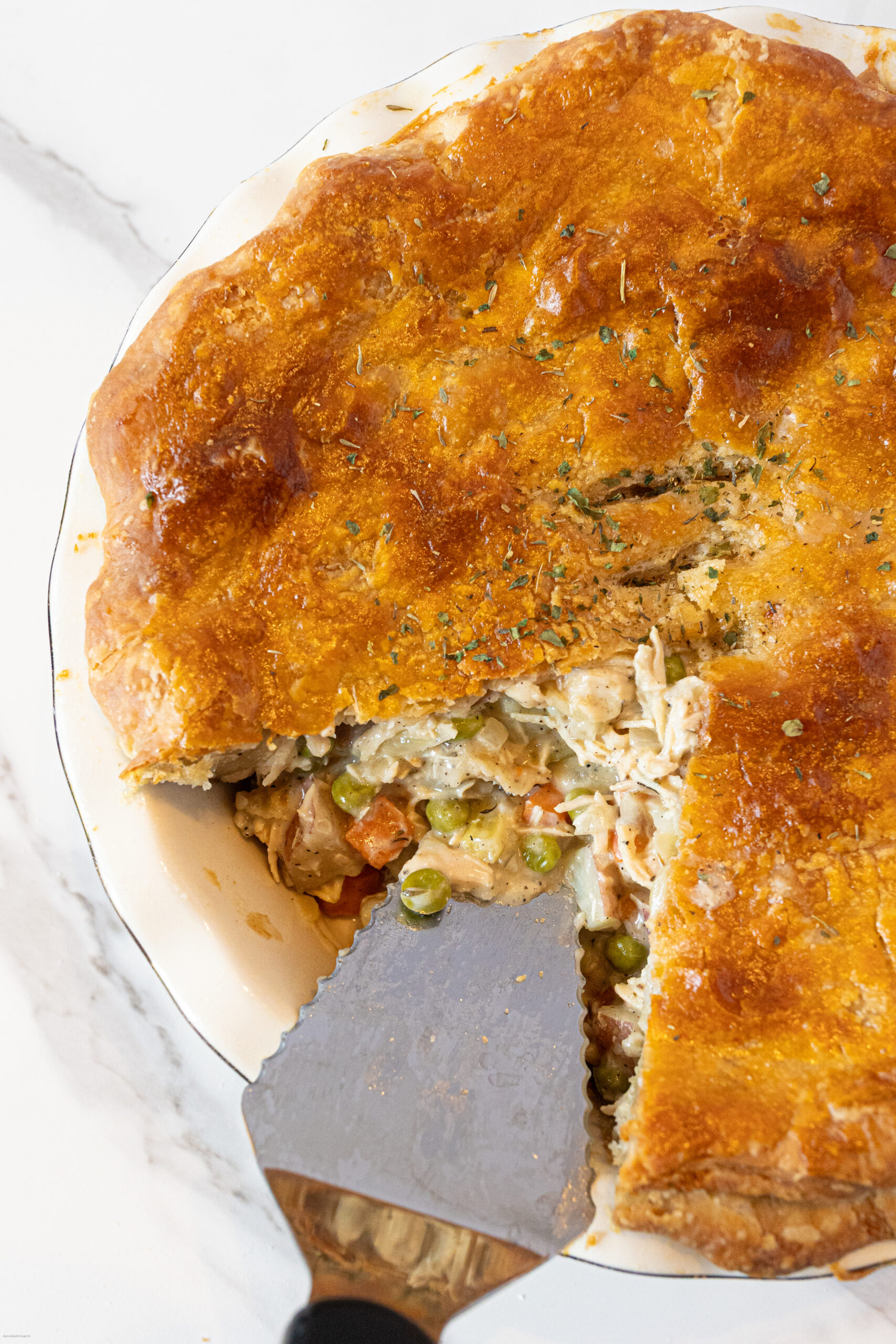homemade chicken pot pie after baking with a serving utensil in it