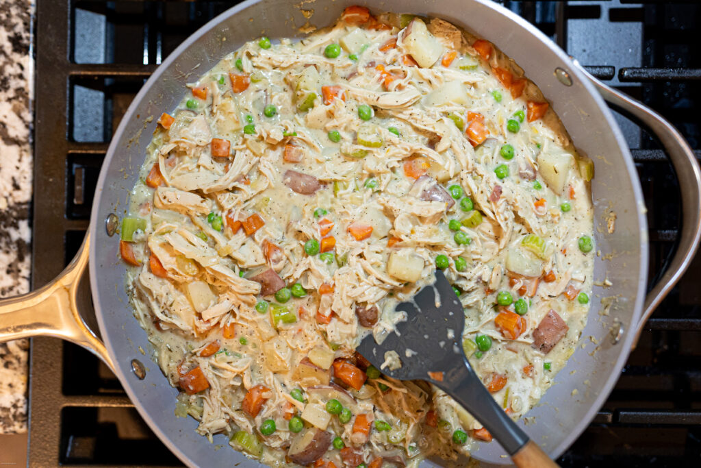 Chicken pot pie filling in a pan on a stove