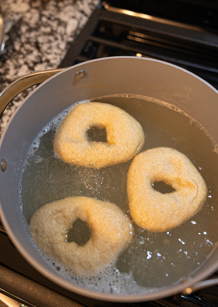 Raw bagels in a pot of water